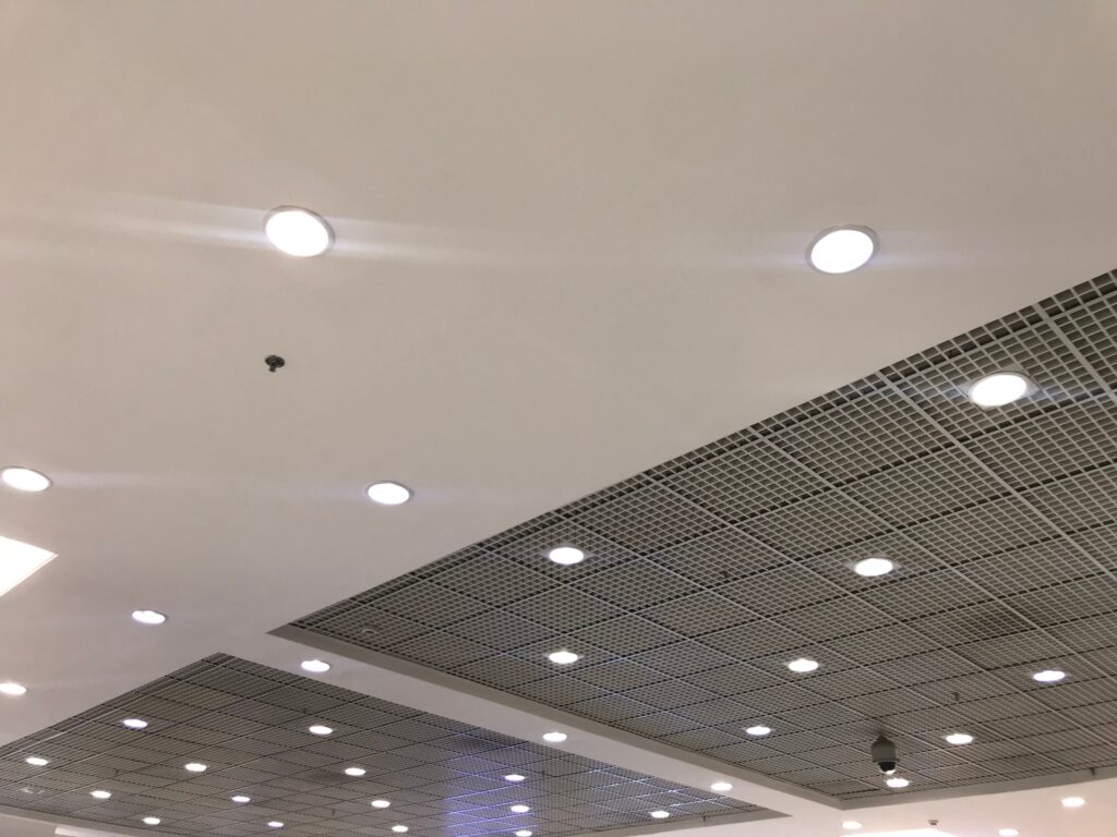 Commercial ceiling with recessed lights, gypsum panels and an open-grid section.