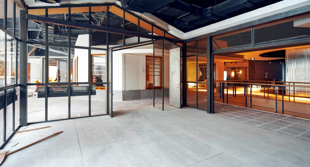 Commercial interior under construction with steel-framed glass partitions and exposed building systems.