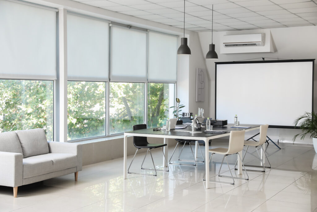 Bright conference room with a meeting table, lounge seating and large windows.