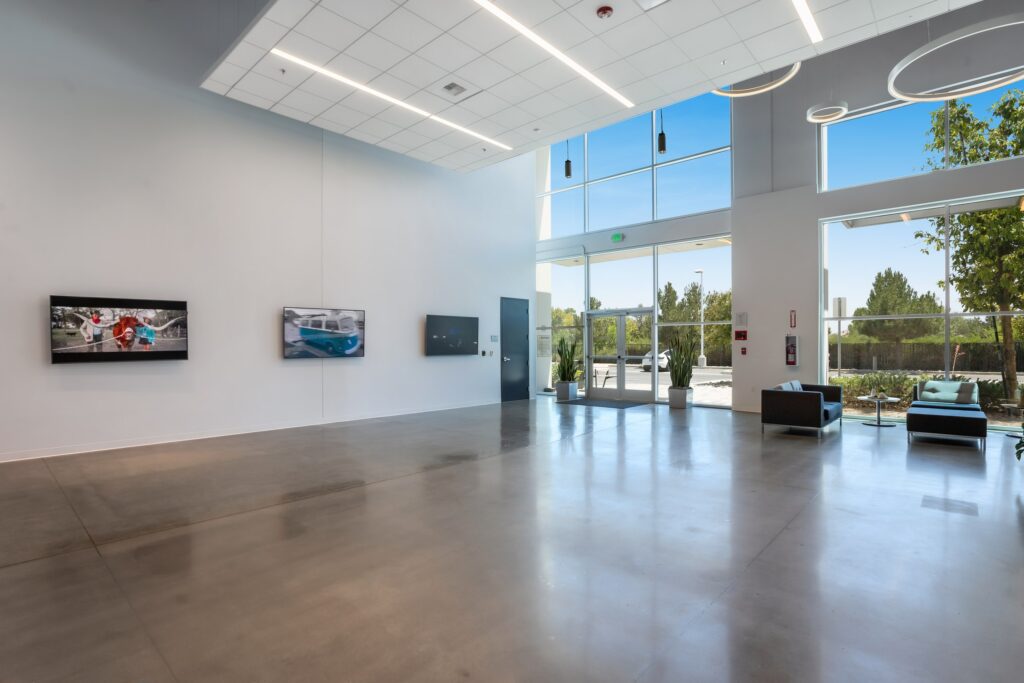 Spacious lobby with glazed entry doors, tall windows, lounge seating and polished flooring.