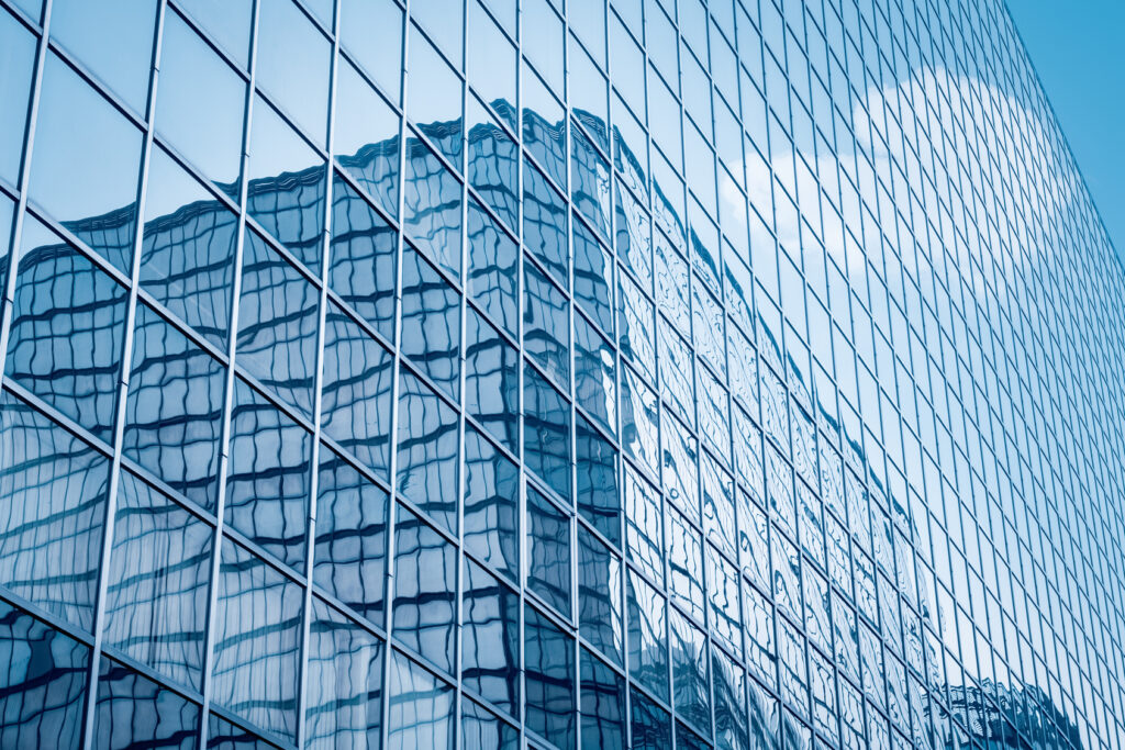 Glass curtain-wall facade with metal framing and reflected buildings