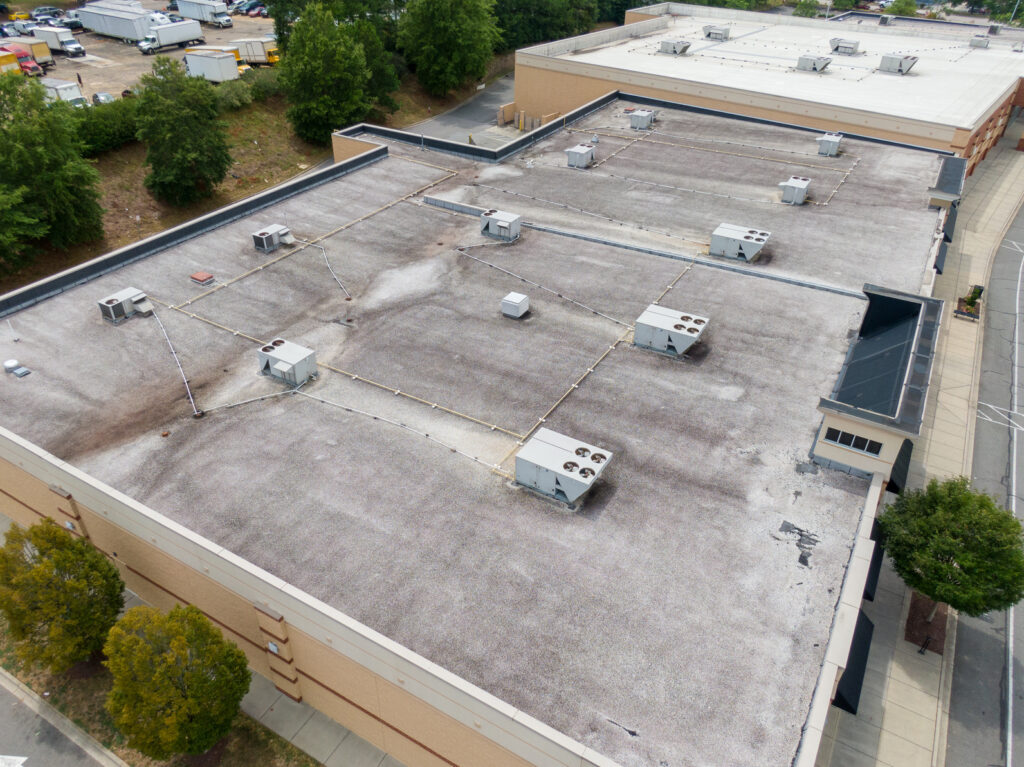 Aerial view of a low-slope commercial roof with multiple rooftop HVAC units.