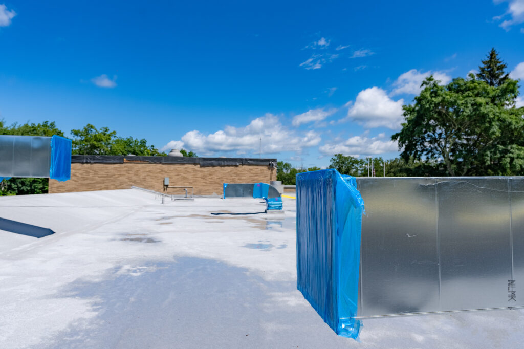 Sheet-metal rooftop equipment curbs on a pale roof membrane.