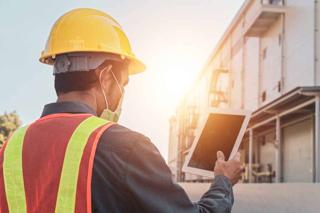 Worker using a tablet beside an industrial building