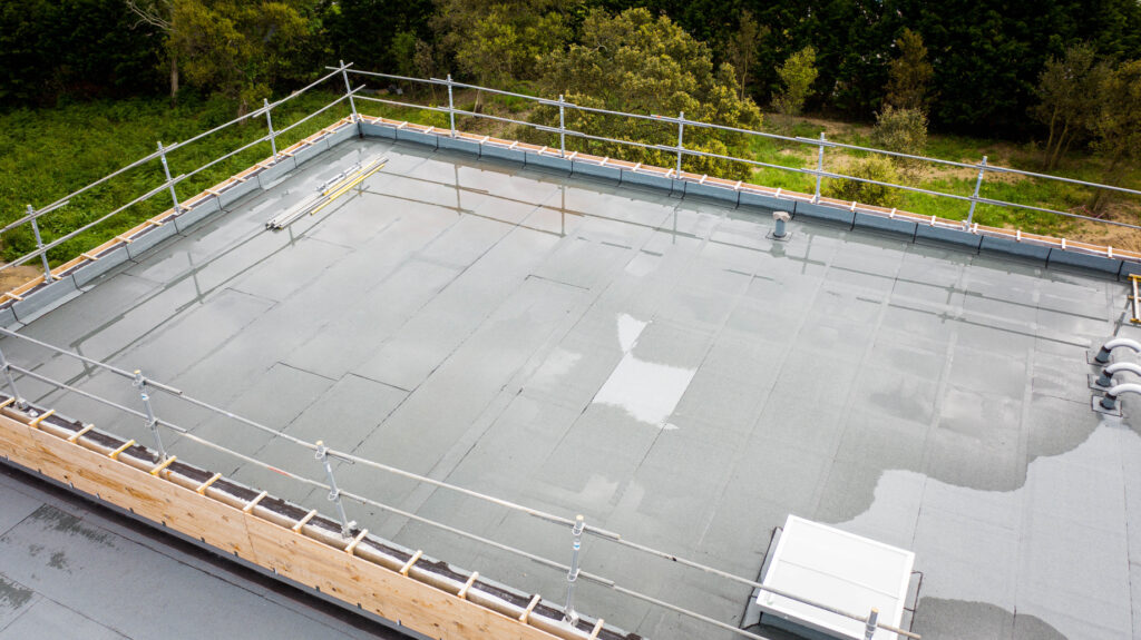 Standing water across sections of a flat industrial roof inside perimeter guardrails.