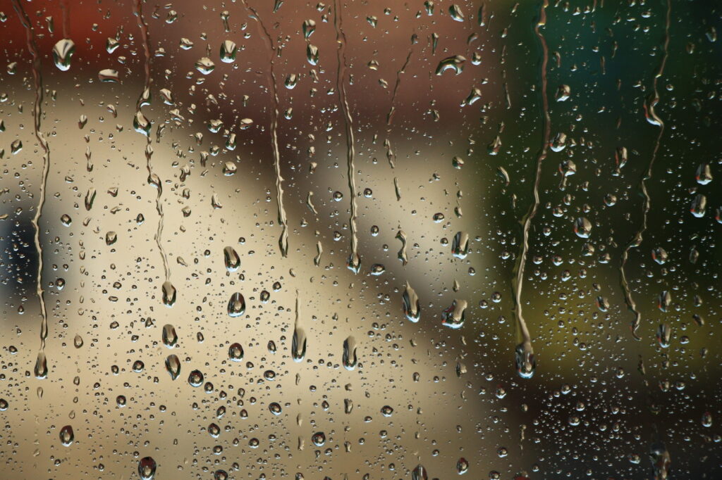 Raindrops and water trails on window glass.