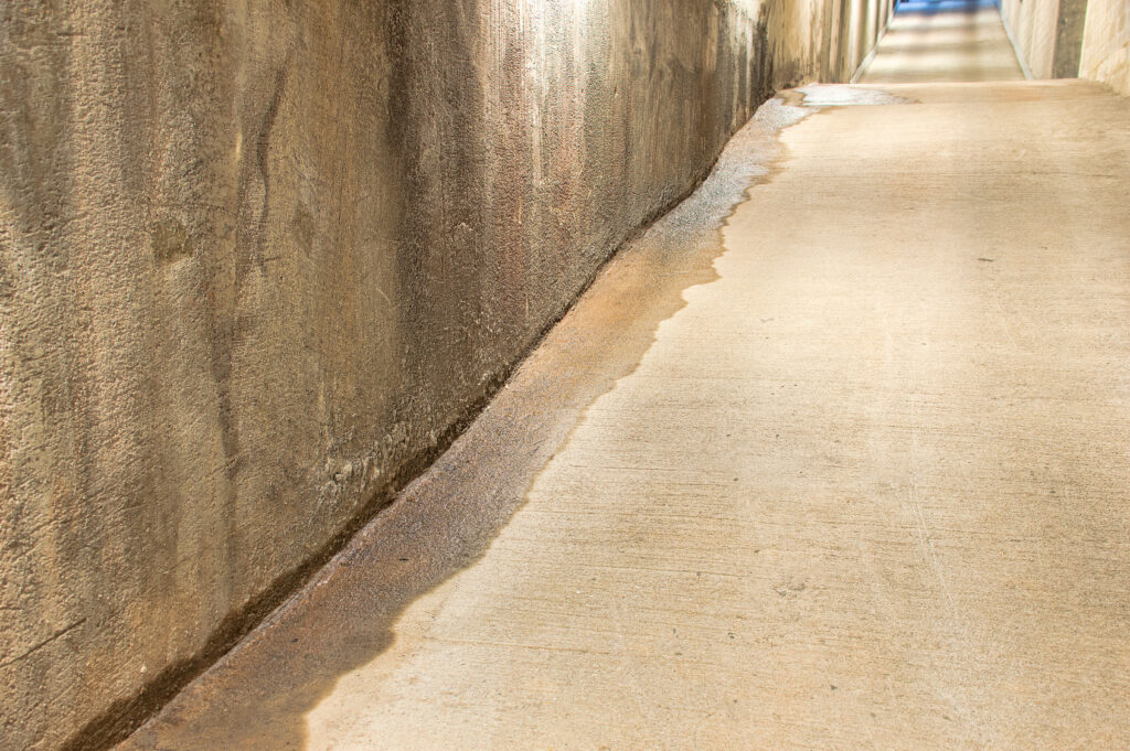 Water staining and a wet floor along a concrete passage wall